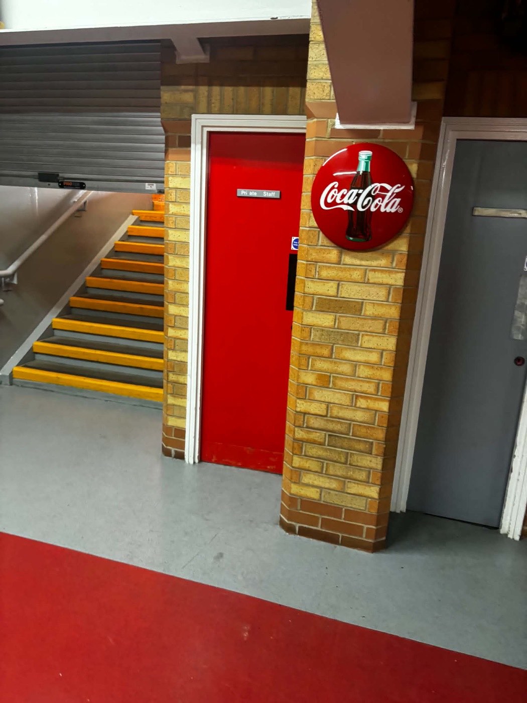 A finished staff door and painted brickwork beside the concourse stairs