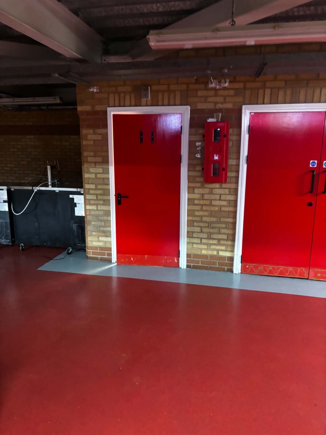 Red doors and frames beside a kiosk servery inside the stadium